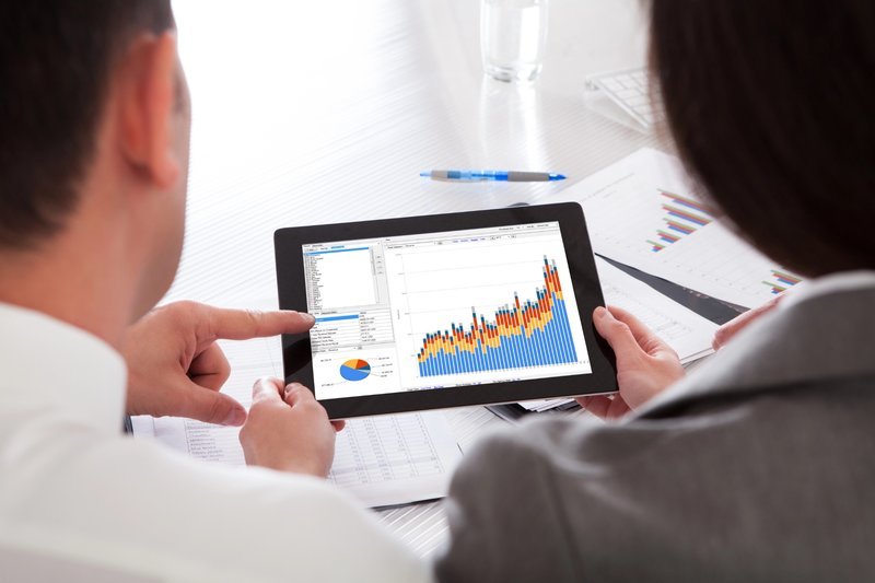 Two business professionals reviewing digital marketing performance graphs on a table